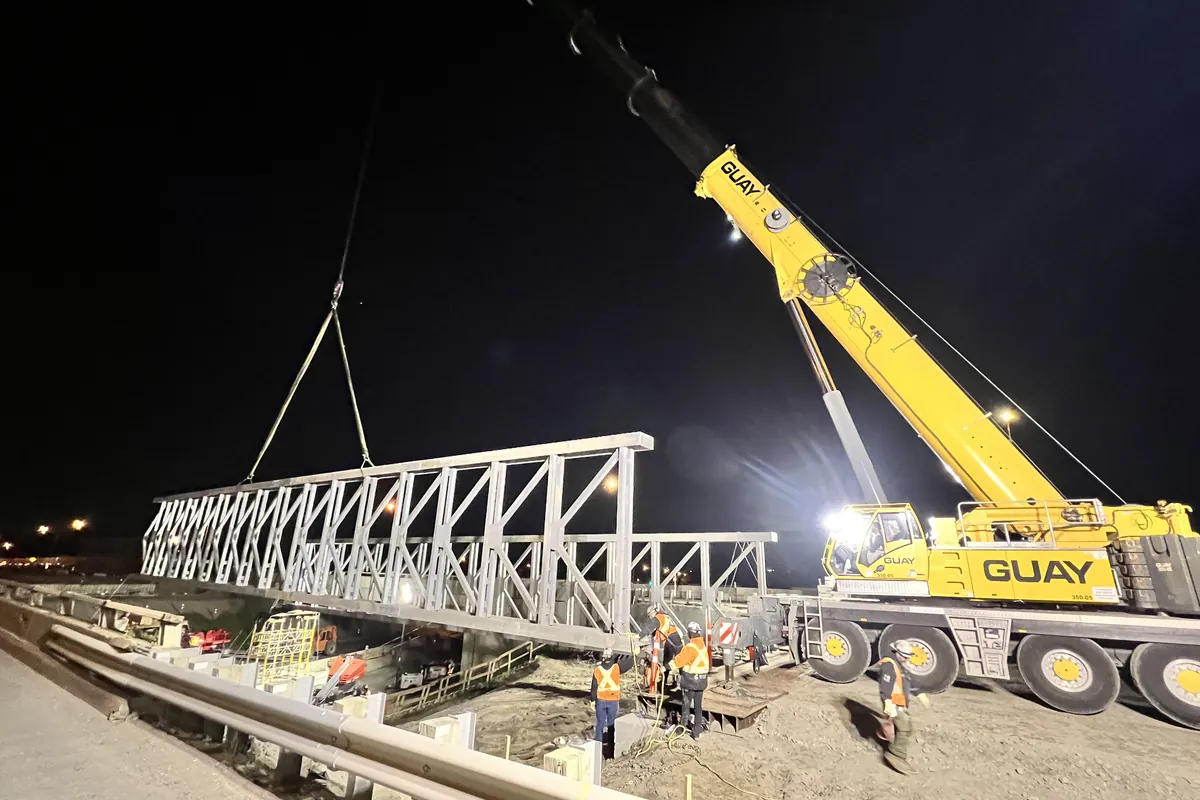 Temporary bridge deck lifted by mobile crane over the roadway