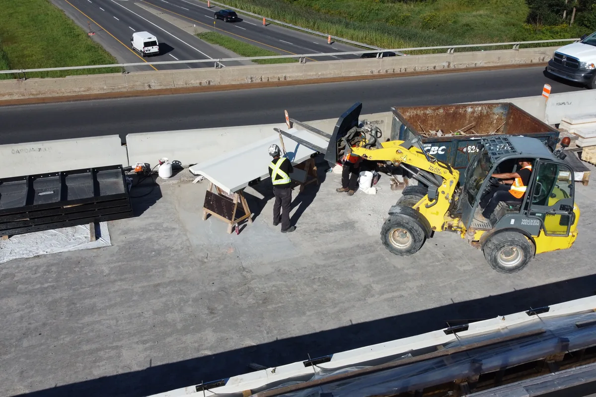Chargeuse compacte et matériaux de construction circulant sur le tablier d’un ouvrage en service